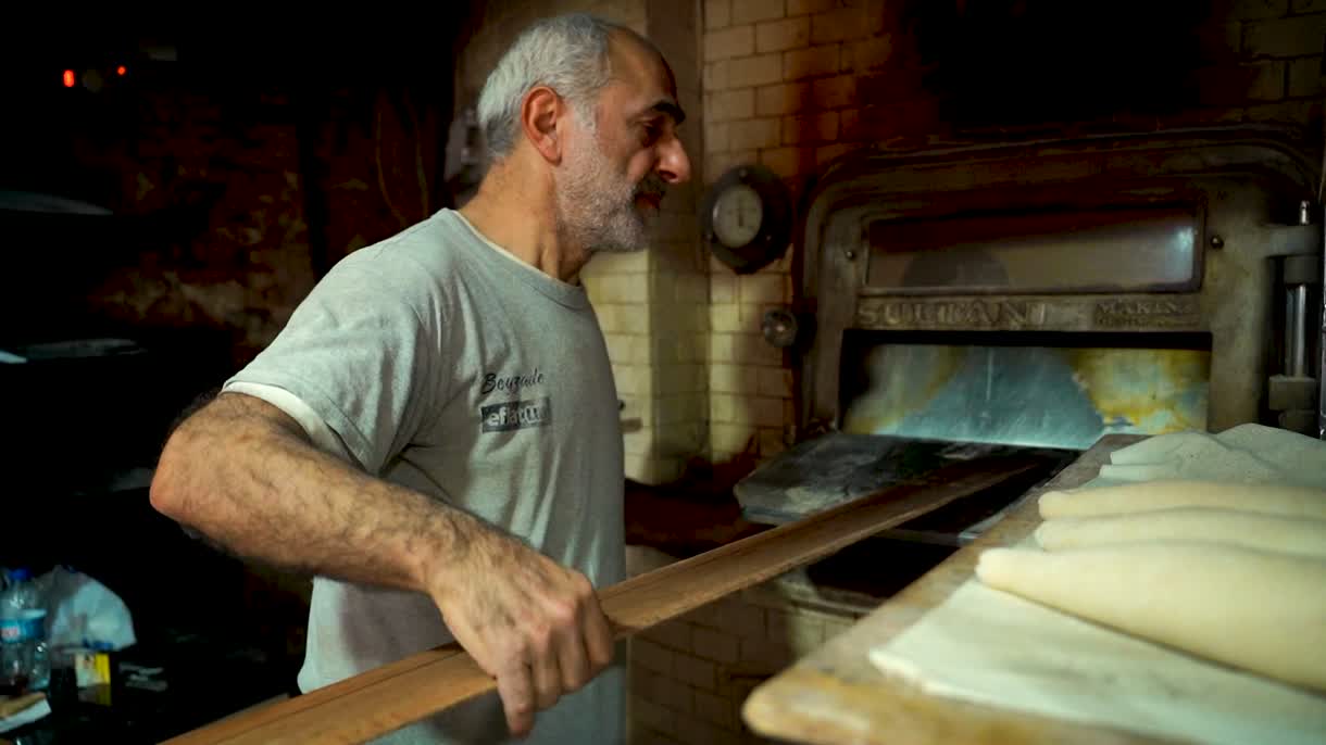 Brotlaibe werden mit dem Holzschieber in den Steinofen eingeschossen